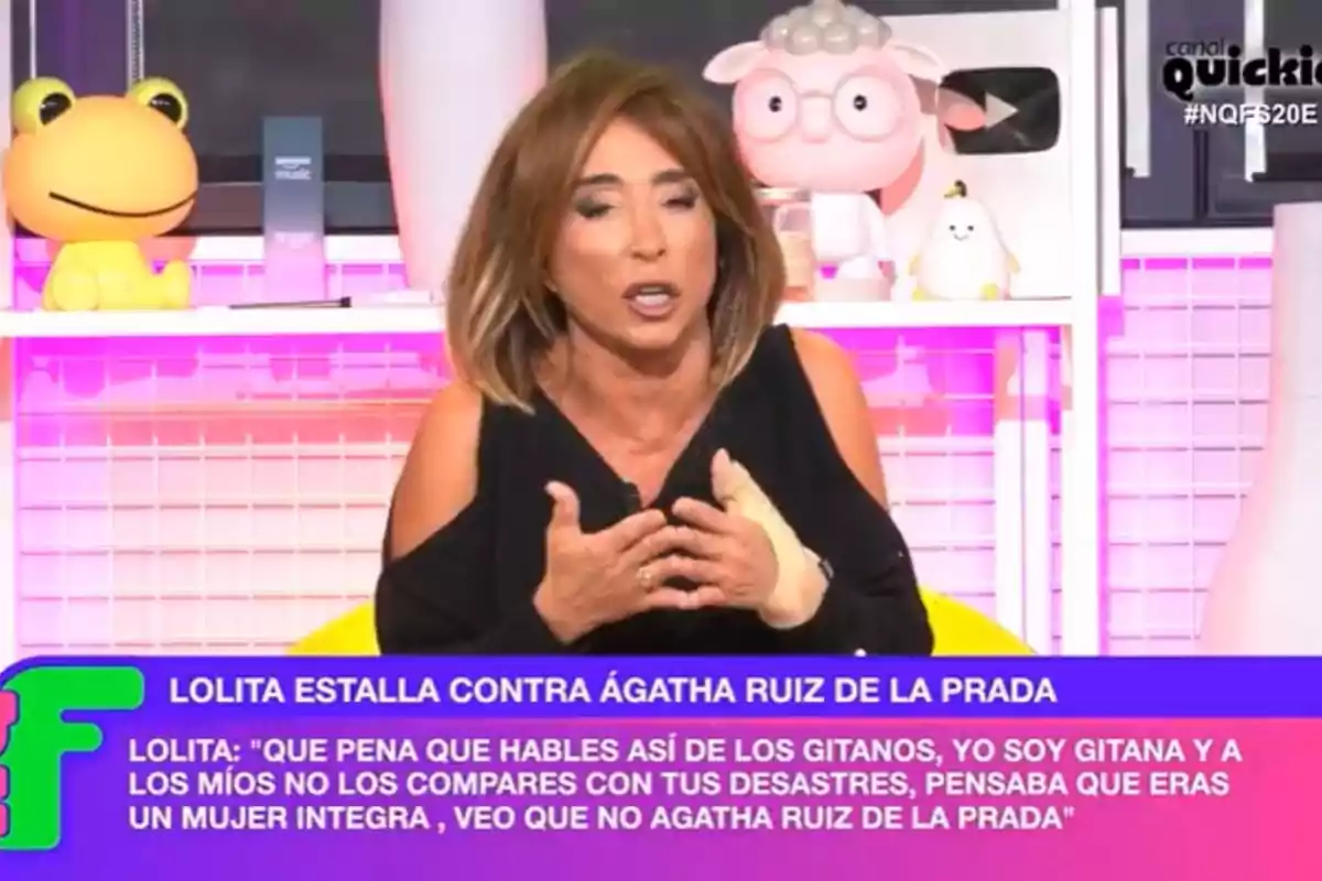 A woman with brown hair and a bandage on her hand is talking on a TV show, with decorative toys in the background and text at the bottom of the screen. A woman with brown hair and a bandage on her hand is talking on a TV show, with decorative toys in the background and text at the bottom of the screen.