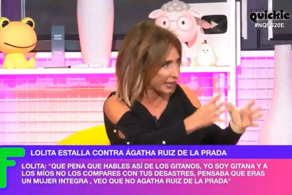 A woman gesturing on a TV show with a colorful background and text at the bottom mentioning a statement by Lolita about Ágatha Ruiz de la Prada. A woman gesturing on a TV show with a colorful background and text at the bottom mentioning a statement by Lolita about Ágatha Ruiz de la Prada.
