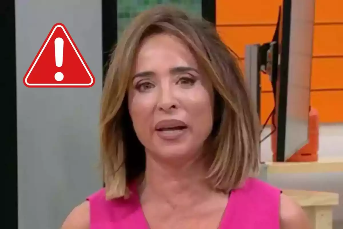 María Patiño con expresión seria en un estudio de televisión con un símbolo de advertencia rojo a su lado