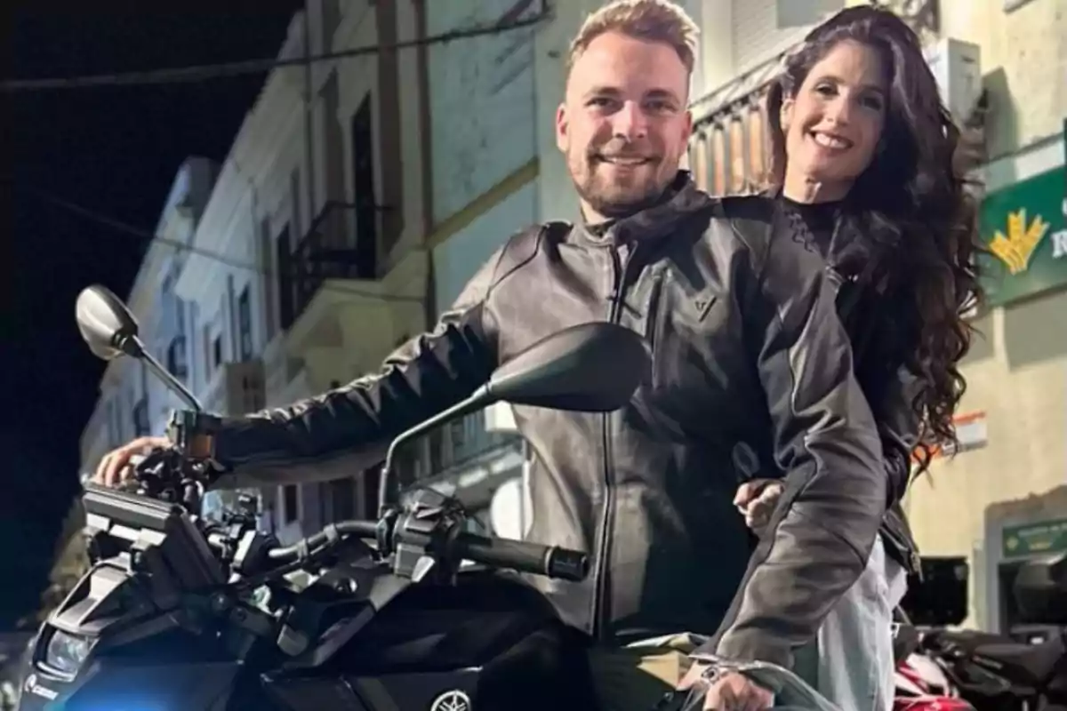 José María Almoguera y María ‘La Jerezana’ sonrientes en una motocicleta en una calle iluminada por la noche. José María Almoguera y María ‘La Jerezana’ sonrientes en una motocicleta en una calle iluminada por la noche.