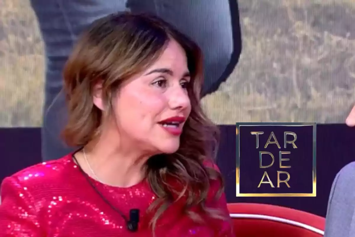 A person in a bright red dress is speaking on a television show with the "TARDEAR" logo visible beside them.