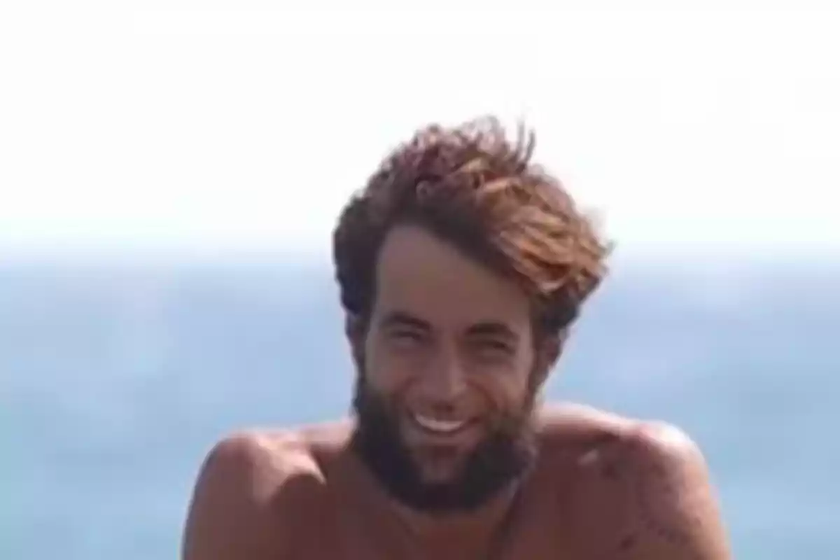 Montoya joven con barba y cabello despeinado sonriendo frente al mar Montoya joven con barba y cabello despeinado sonriendo frente al mar
