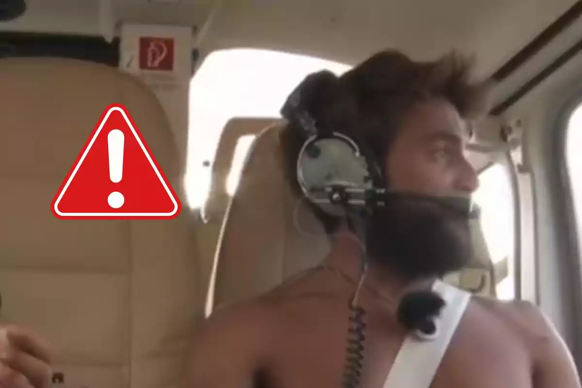 Montoya con auriculares y micrófono dentro de una cabina de helicóptero sin camiseta y un símbolo de advertencia en la imagen