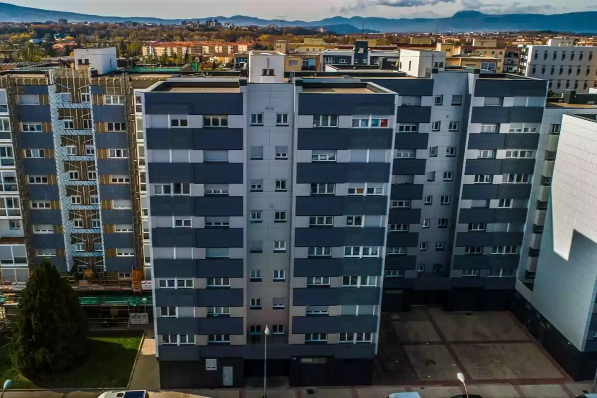 Edificios residenciales de varios pisos con un fondo de paisaje urbano y montañas.