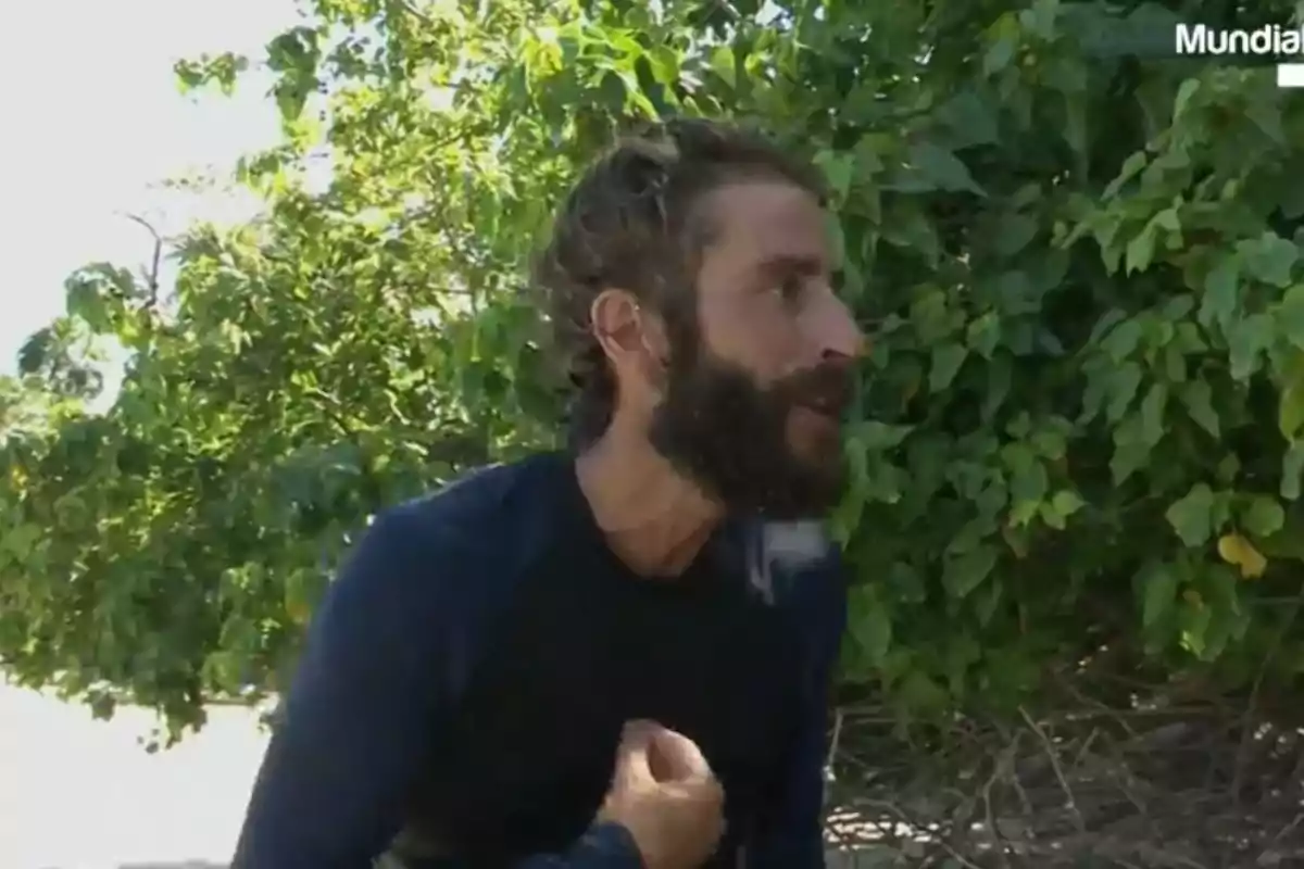 Pelayo Díaz con barba y cabello despeinado vestido con camiseta oscura gesticulando frente a un fondo de vegetación verde Pelayo Díaz con barba y cabello despeinado vestido con camiseta oscura gesticulando frente a un fondo de vegetación verde