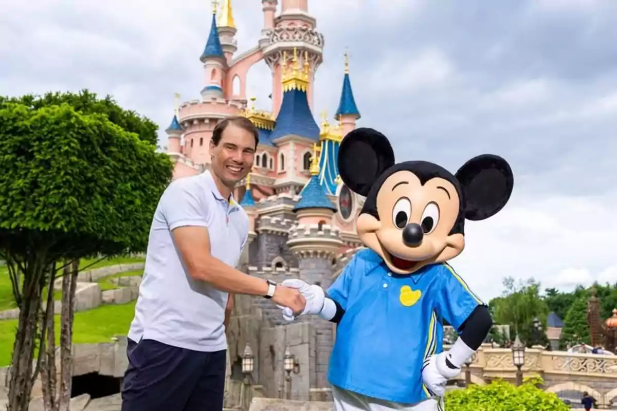 A smiling man shakes hands with Mickey Mouse in front of a castle at a theme park. A smiling man shakes hands with Mickey Mouse in front of a castle at a theme park.