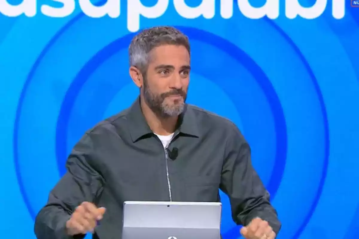 Roberto Leal de cabello canoso y barba sentado frente a una computadora con fondo azul y letras blancas Roberto Leal de cabello canoso y barba sentado frente a una computadora con fondo azul y letras blancas