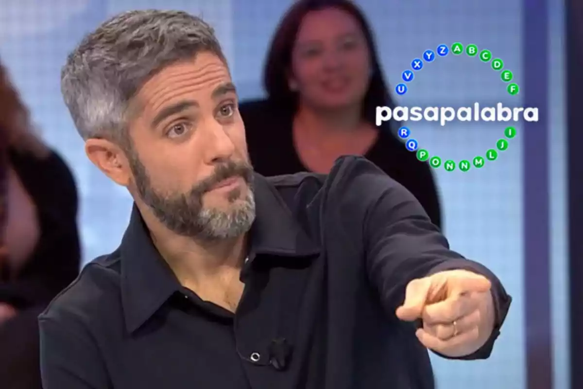 Roberto Leal con barba y cabello canoso señala hacia adelante en un set de televisión con el logo de "Pasapalabra" en el fondo.