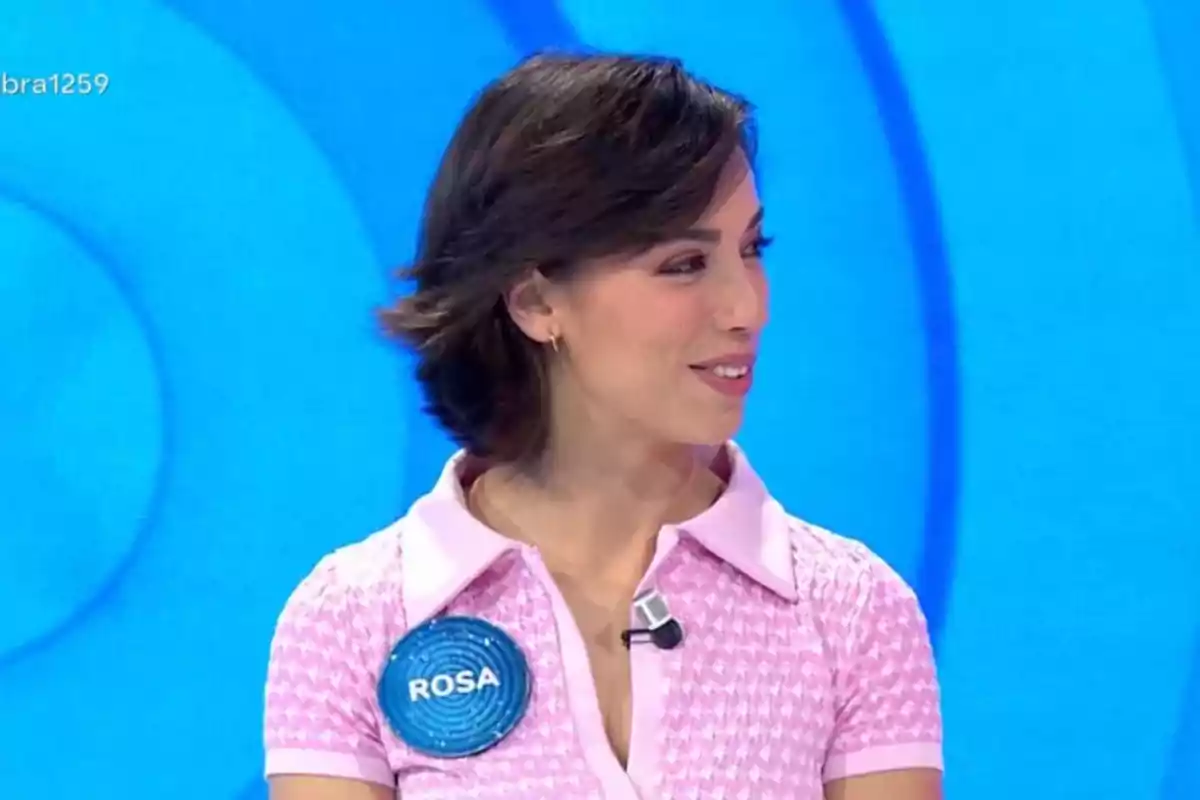 Rosa con cabello corto y oscuro lleva una camisa rosa con un micrófono en un programa de televisión. Rosa con cabello corto y oscuro lleva una camisa rosa con un micrófono en un programa de televisión.