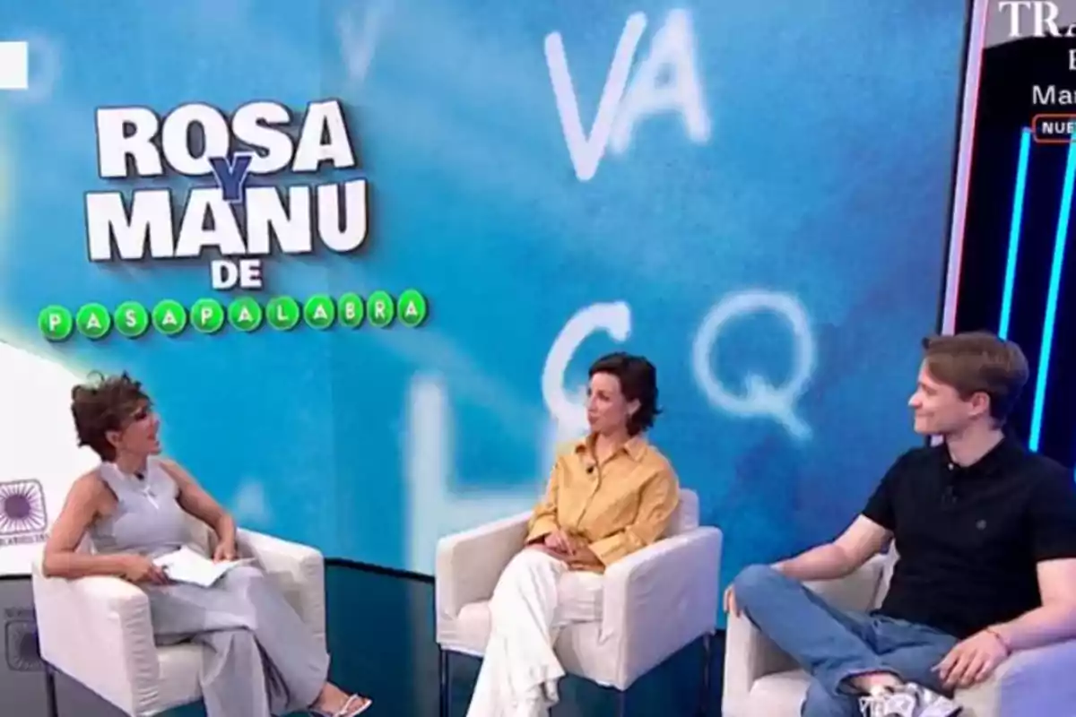 Tres personas sentadas en sillones blancos conversan en un set de televisión con un fondo azul que tiene letras y el texto ROSA Y MANU DE PASAPALABRA Tres personas sentadas en sillones blancos conversan en un set de televisión con un fondo azul que tiene letras y el texto ROSA Y MANU DE PASAPALABRA