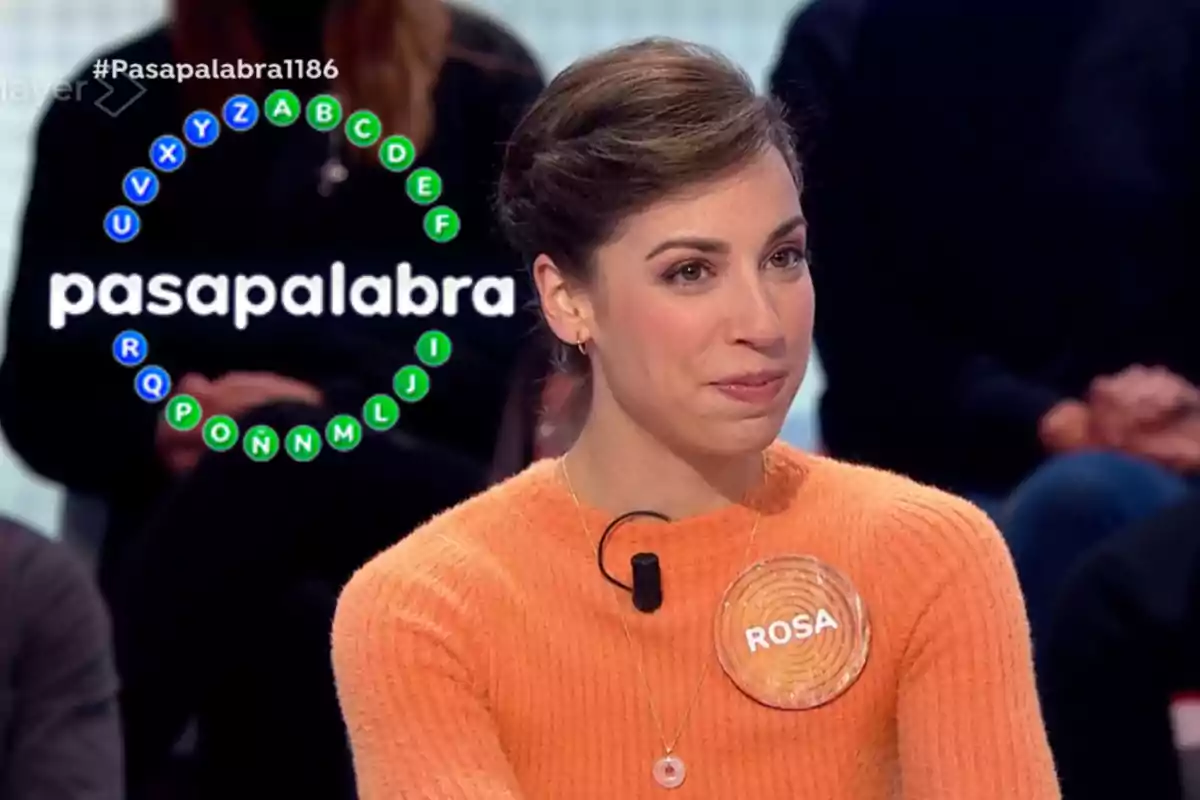 Rosa con un suéter naranja participa en un programa de televisión llamado "Pasapalabra" con un círculo de letras en el fondo.