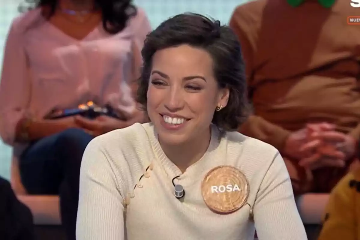 Rosa sonriente con un micrófono en la ropa y un cartel que dice Rosa sonriente con un micrófono en la ropa y un cartel que dice