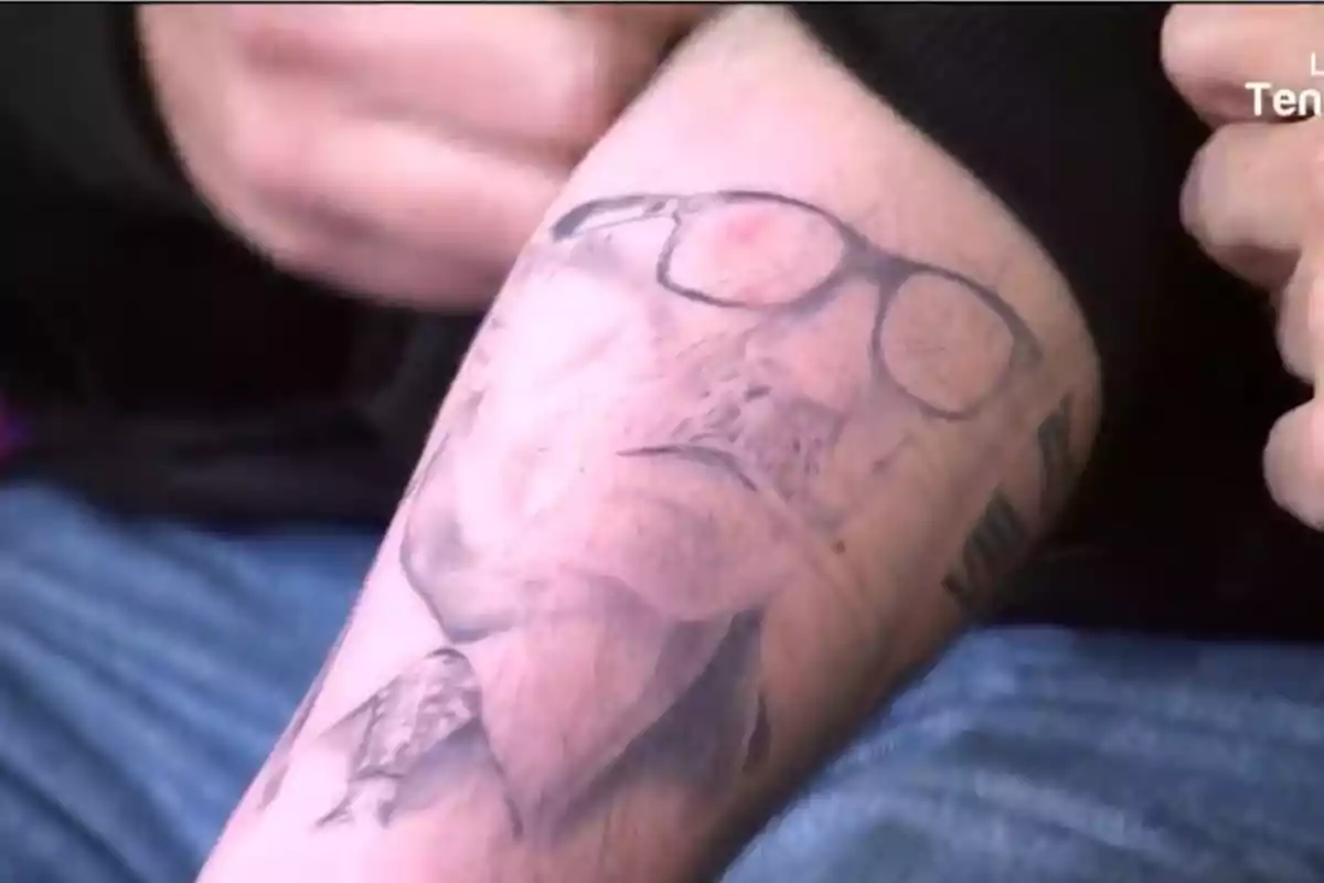 Un brazo con un tatuaje de un rostro con gafas. Un brazo con un tatuaje de un rostro con gafas.
