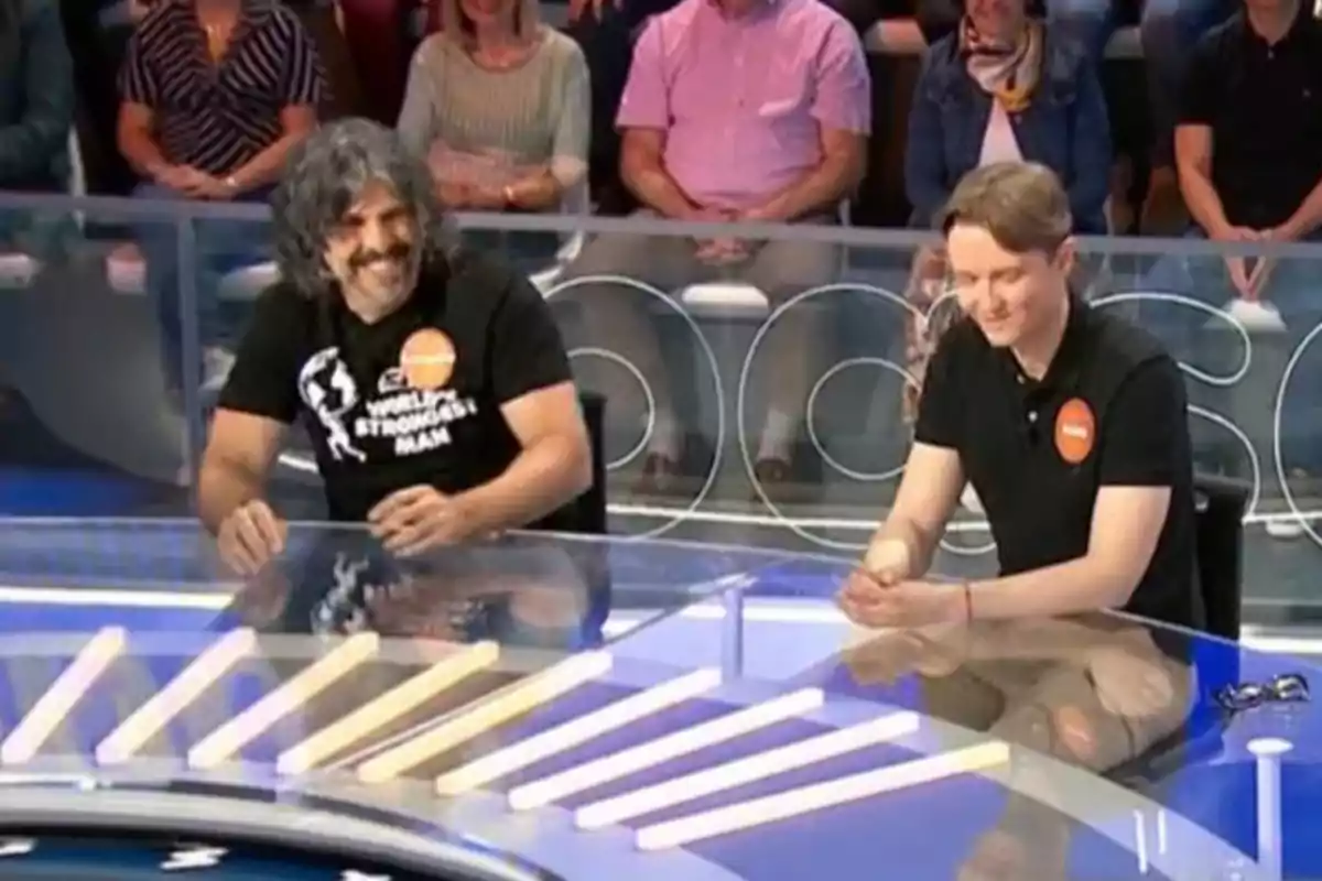 Vaquero y Manu sentados en una mesa transparente durante un programa de televisión con público al fondo Vaquero y Manu sentados en una mesa transparente durante un programa de televisión con público al fondo