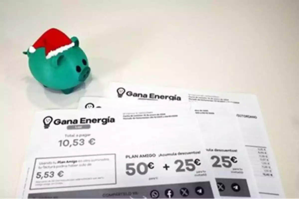 Un cerdito de color verde con un gorro navideño junto a varias facturas de Gana Energía sobre una mesa.