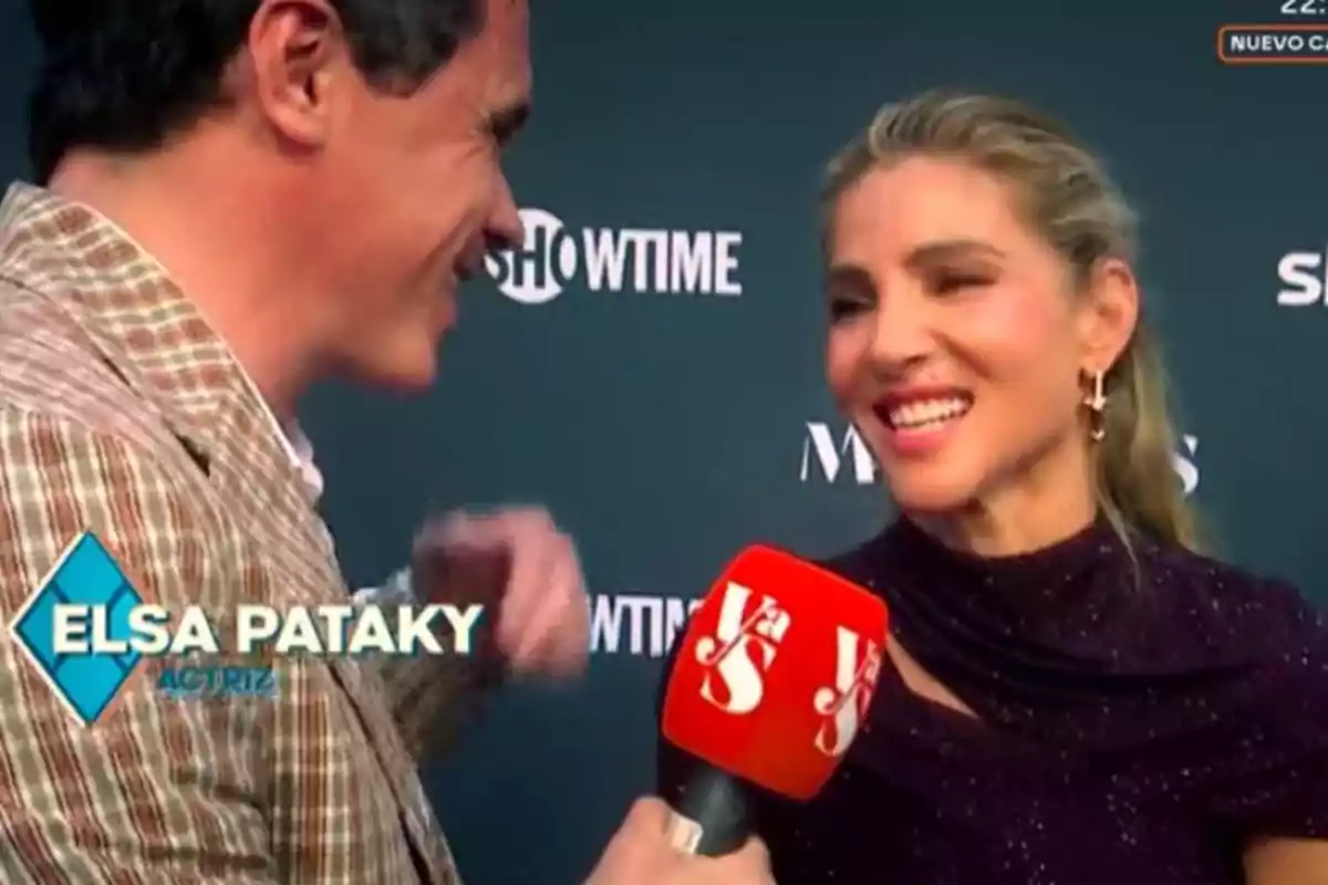 Elsa Pataky sonríe mientras es entrevistada por un hombre en un evento con fondo de logotipos y un micrófono rojo. Elsa Pataky sonríe mientras es entrevistada por un hombre en un evento con fondo de logotipos y un micrófono rojo.