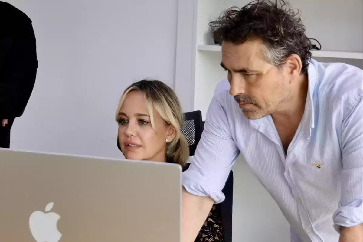 Dos personas trabajando juntas frente a una computadora portátil.