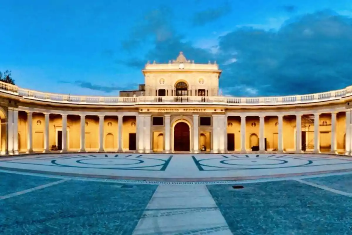 Edificio histórico con columnas iluminadas al atardecer y cielo azul.