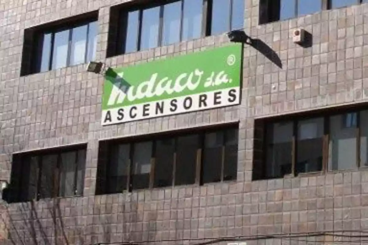 Edificio de ladrillo con un cartel verde y blanco que dice "Ascensores".