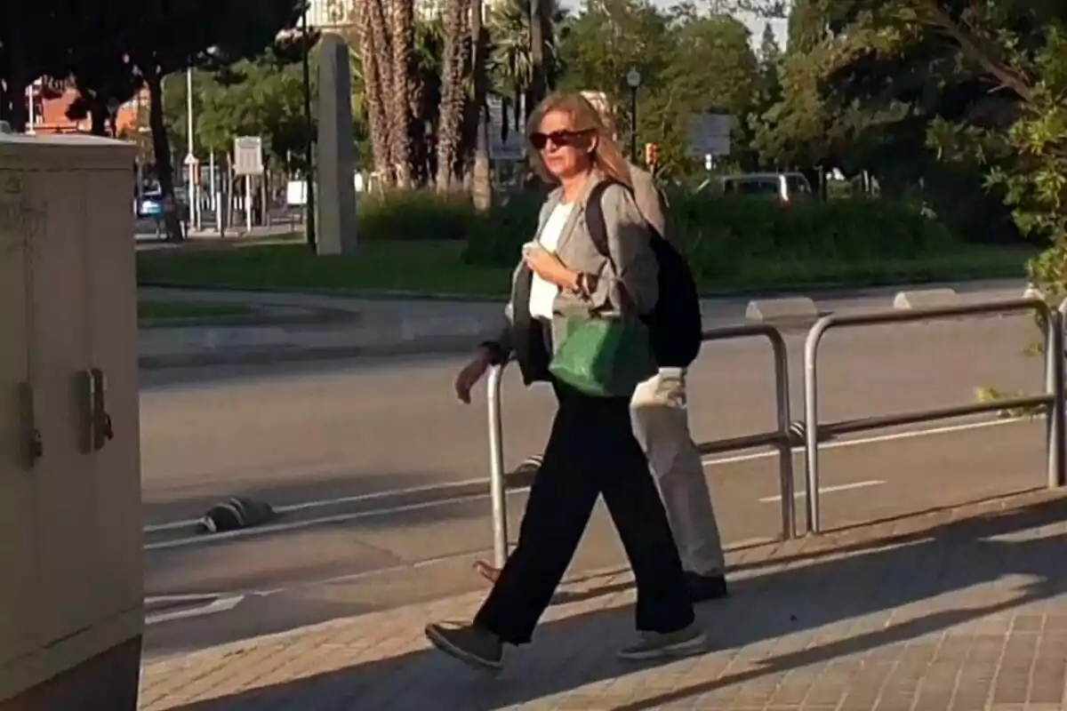 La infanta Cristina camina por la acera en un día soleado llevando gafas de sol y un bolso verde. La infanta Cristina camina por la acera en un día soleado llevando gafas de sol y un bolso verde.