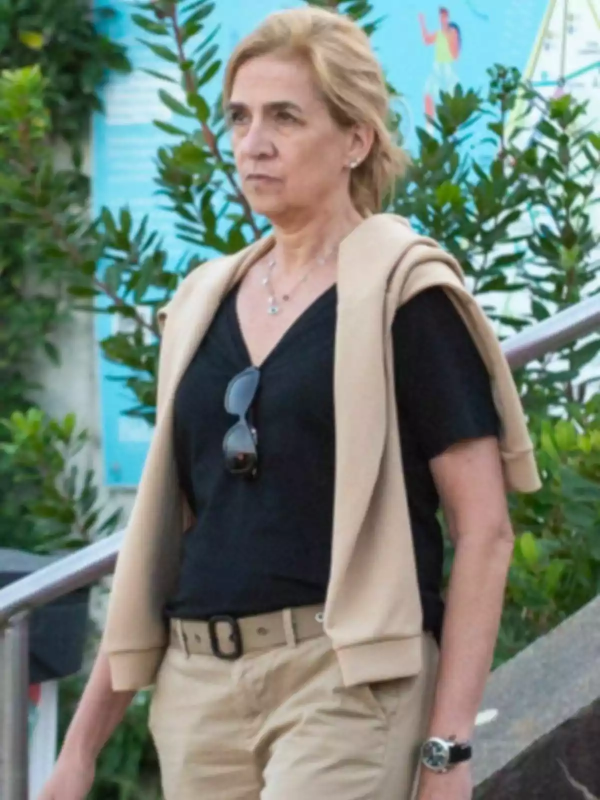 La infanta Cristina de expresión seria caminando al aire libre con pantalón beige, camiseta negra y suéter claro sobre los hombros La infanta Cristina de expresión seria caminando al aire libre con pantalón beige, camiseta negra y suéter claro sobre los hombros
