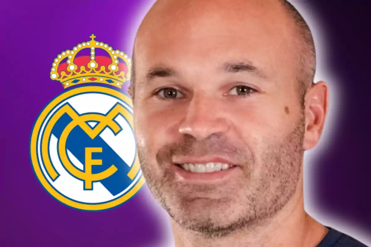 Un hombre sonriente con barba frente a un fondo morado y el escudo del Real Madrid.