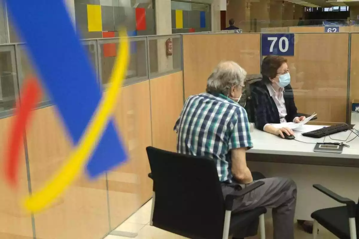 Interior de unas oficinas de la Agencia Tributaria con una funcionaria atendiendo un contribuyente Interior de unas oficinas de la Agencia Tributaria con una funcionaria atendiendo un contribuyente