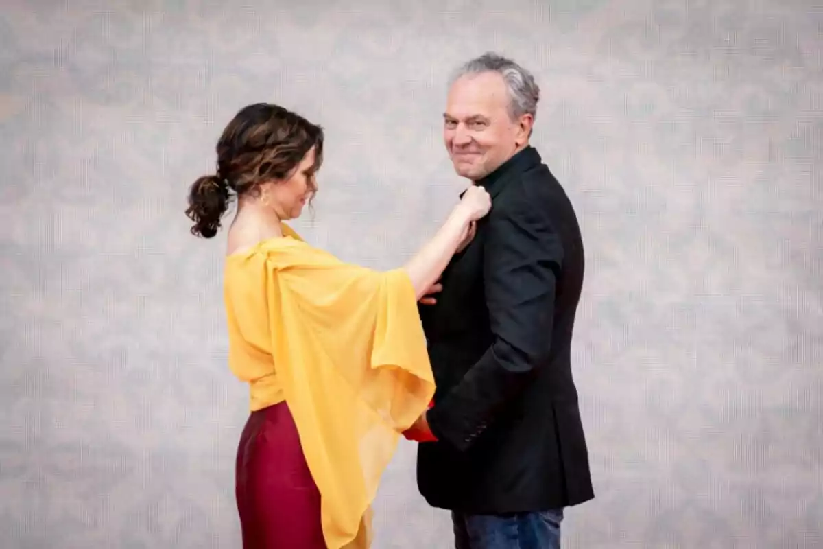Isabel Díaz Ayuso con blusa amarilla ajusta la solapa del saco de José Coronado que sonríe. Isabel Díaz Ayuso con blusa amarilla ajusta la solapa del saco de José Coronado que sonríe.