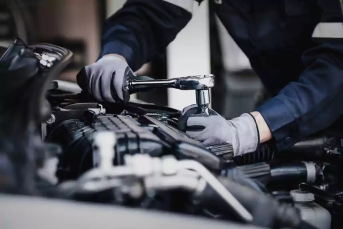 Mecánico trabajando en el motor de un automóvil con una llave inglesa.