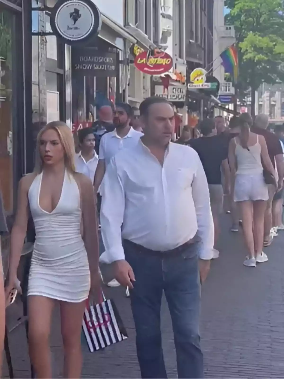 People walking down a busy street with colorful shops and signs.