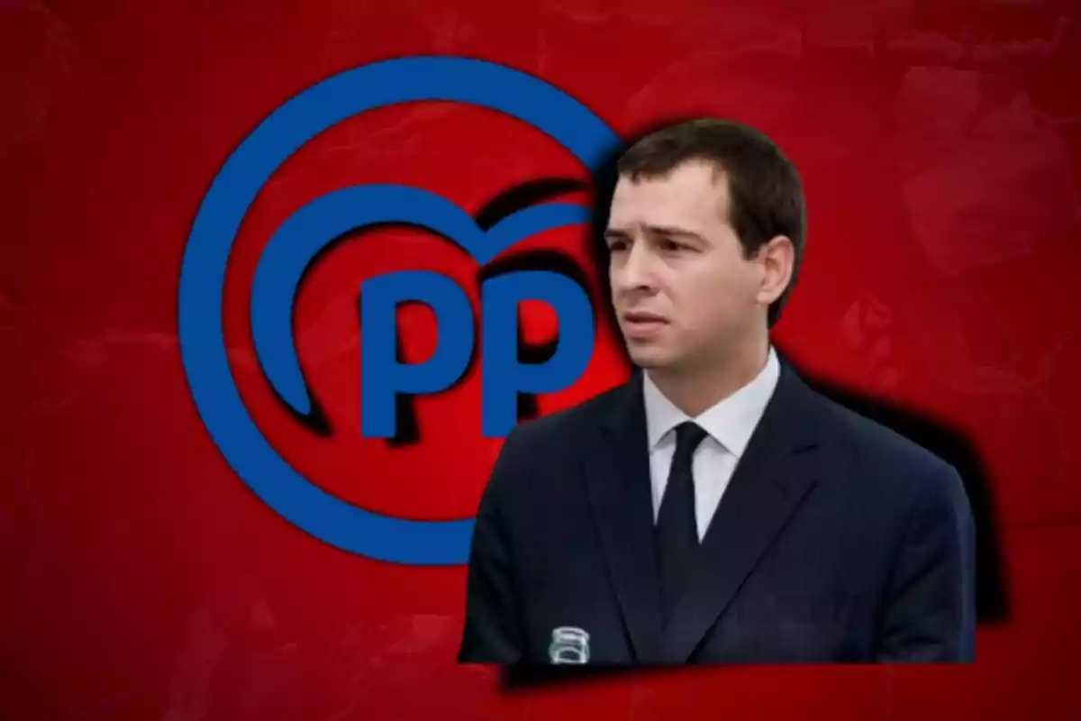 Un hombre con traje oscuro y corbata aparece frente a un logotipo azul del Partido Popular sobre un fondo rojo.