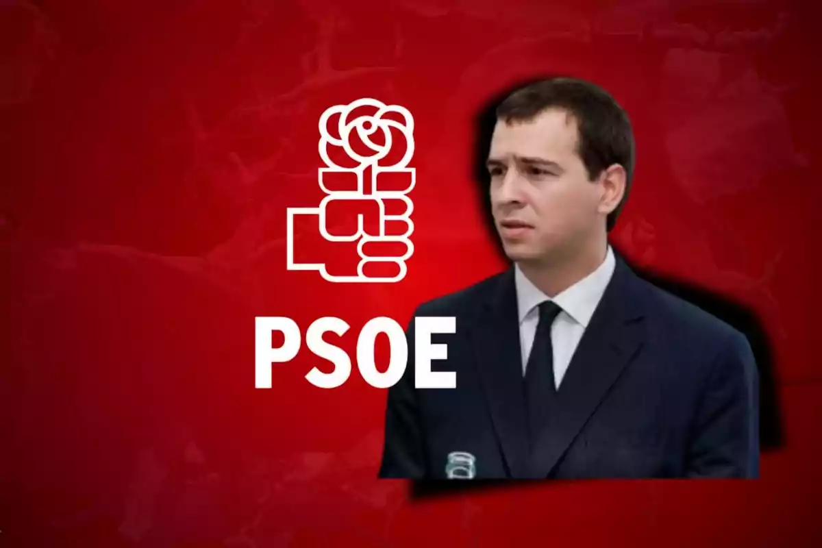 Hombre con traje oscuro y corbata frente a un fondo rojo con el logo del PSOE y una rosa.