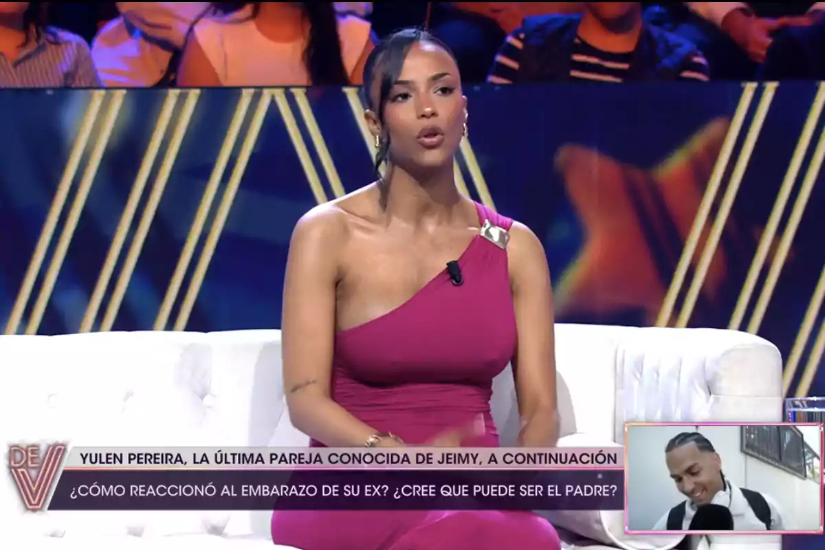 Jeimy Báez con un vestido rosa está sentada en un sofá blanco en un programa de televisión. En la parte inferior de la imagen hay un texto que menciona a Yulen Pereira y una pregunta sobre el embarazo de su ex. En la esquina inferior derecha hay una pequeña imagen de un hombre sonriendo. Jeimy Báez con un vestido rosa está sentada en un sofá blanco en un programa de televisión. En la parte inferior de la imagen hay un texto que menciona a Yulen Pereira y una pregunta sobre el embarazo de su ex. En la esquina inferior derecha hay una pequeña imagen de un hombre sonriendo.