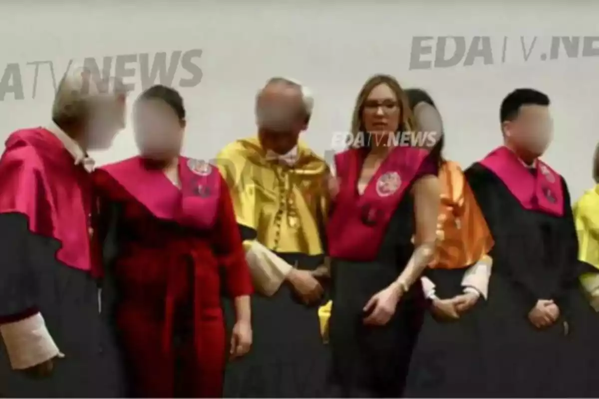 A group of people in academic robes of various colors pose for a photo at a formal event.