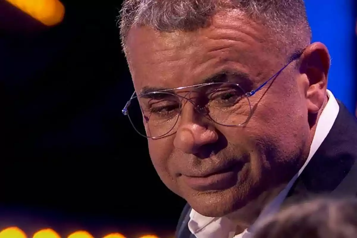 Jorge Javier Vázquez con gafas y expresión seria en un ambiente iluminado en Hay una cosa que te quiero decir. Jorge Javier Vázquez con gafas y expresión seria en un ambiente iluminado en Hay una cosa que te quiero decir.