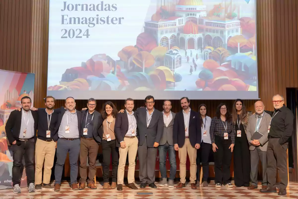 Un grupo de personas posando juntas en un evento llamado Jornadas Emagister 2024, con un fondo que muestra una ilustración colorida de un edificio y árboles.