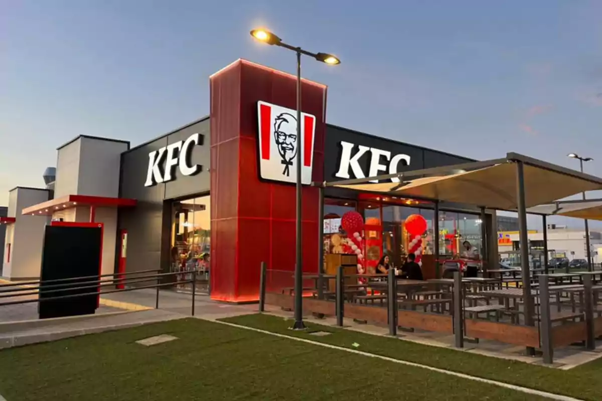 Franquicia de comida rápida KFC con área de comedor al aire libre y decoración de globos rojos y blancos. Franquicia de comida rápida KFC con área de comedor al aire libre y decoración de globos rojos y blancos.