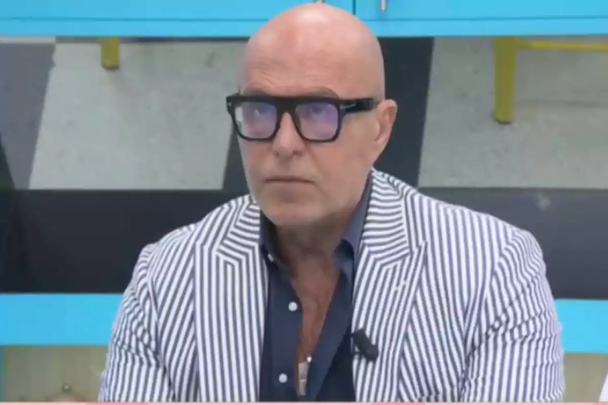 Kiko Matamoros calvo con gafas y saco de rayas blancas y azules sentado en un ambiente interior en 'La familia de la tele'. Kiko Matamoros calvo con gafas y saco de rayas blancas y azules sentado en un ambiente interior en 'La familia de la tele'.