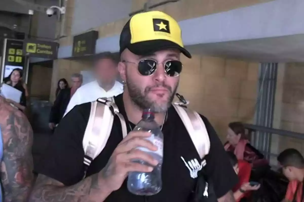 Kiko Rivera serio con una gorra amarilla y negra, gafas de sol y una botella de agua en la mano en el aeropuerto Kiko Rivera serio con una gorra amarilla y negra, gafas de sol y una botella de agua en la mano en el aeropuerto