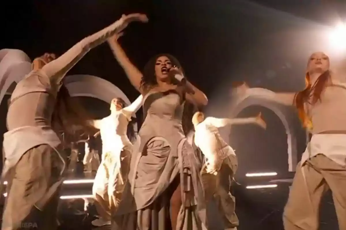 Una cantante, que es Lachispa, en el escenario del 'Benidorm Fest' rodeada de bailarinas con trajes beige y luces brillantes. Una cantante, que es Lachispa, en el escenario del 'Benidorm Fest' rodeada de bailarinas con trajes beige y luces brillantes.