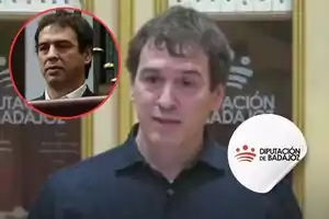 Un hombre hablando frente a un cartel de la Diputación de Badajoz, con un recuadro rojo que muestra a otra persona en la esquina superior izquierda.