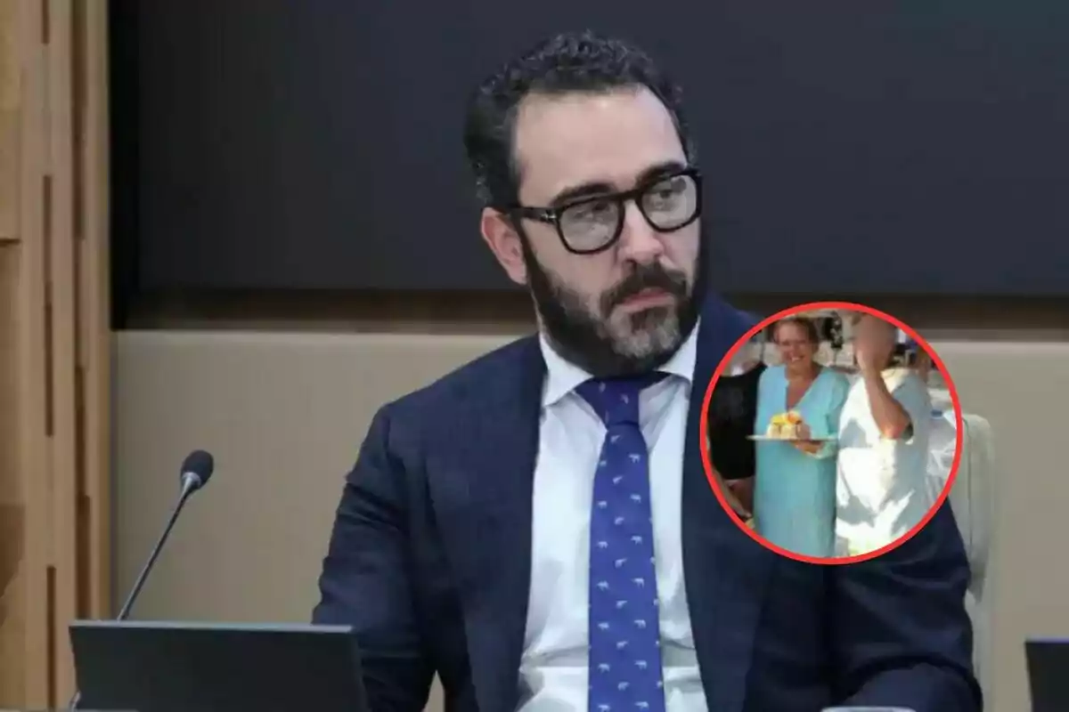 Un hombre con barba y gafas está sentado frente a un micrófono y una computadora, con un recuadro que muestra a una mujer sonriendo mientras sostiene un plato con comida.