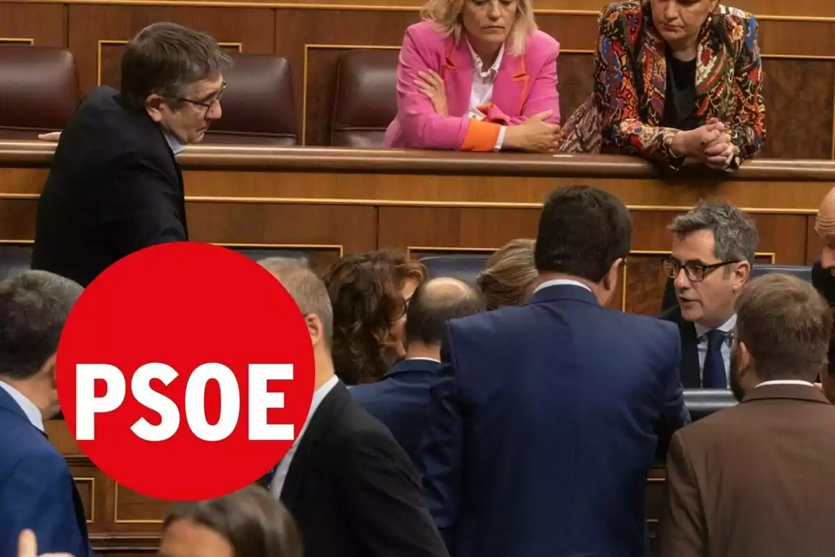 Un grupo de personas conversando en un entorno formal con un logotipo rojo del PSOE superpuesto en primer plano.