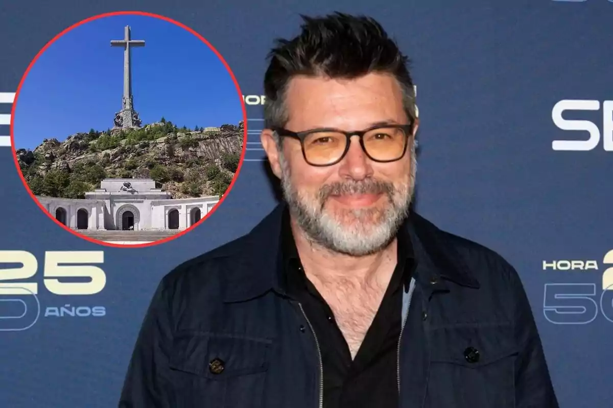 Hombre con gafas y barba posando frente a un fondo azul con un círculo rojo que muestra una imagen del Valle de los Caídos.