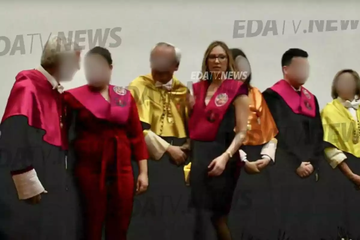 Un grupo de personas vestidas con togas académicas de colores variados posan para una foto en un evento formal.