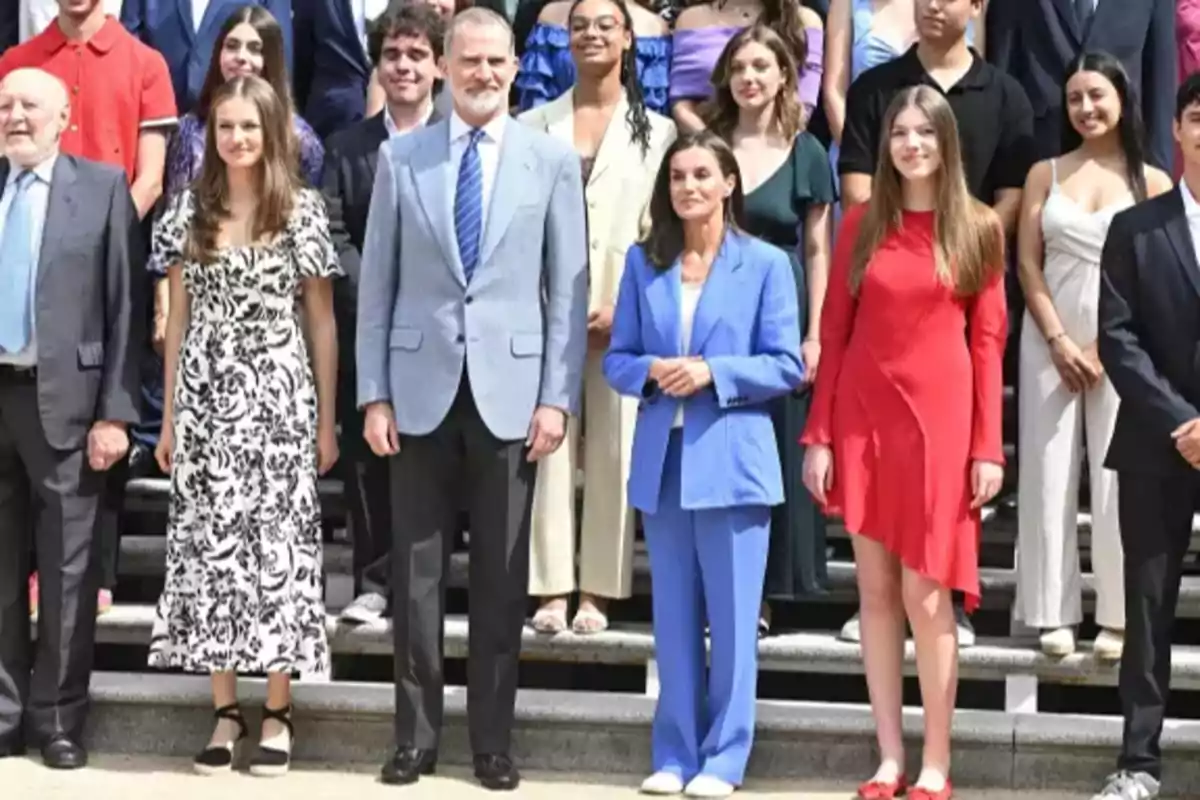 Un grupo de personas posando para una foto en una escalera, con algunos de ellos vestidos formalmente y otros con ropa casual.