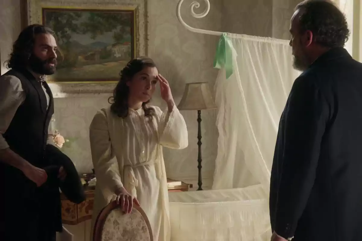 Adriano, Catalina y Alonso conversan en una habitación elegantemente decorada con un cuadro en la pared y una cuna con cortinas blancas. Captura de 'La Promesa' Adriano, Catalina y Alonso conversan en una habitación elegantemente decorada con un cuadro en la pared y una cuna con cortinas blancas. Captura de 'La Promesa'