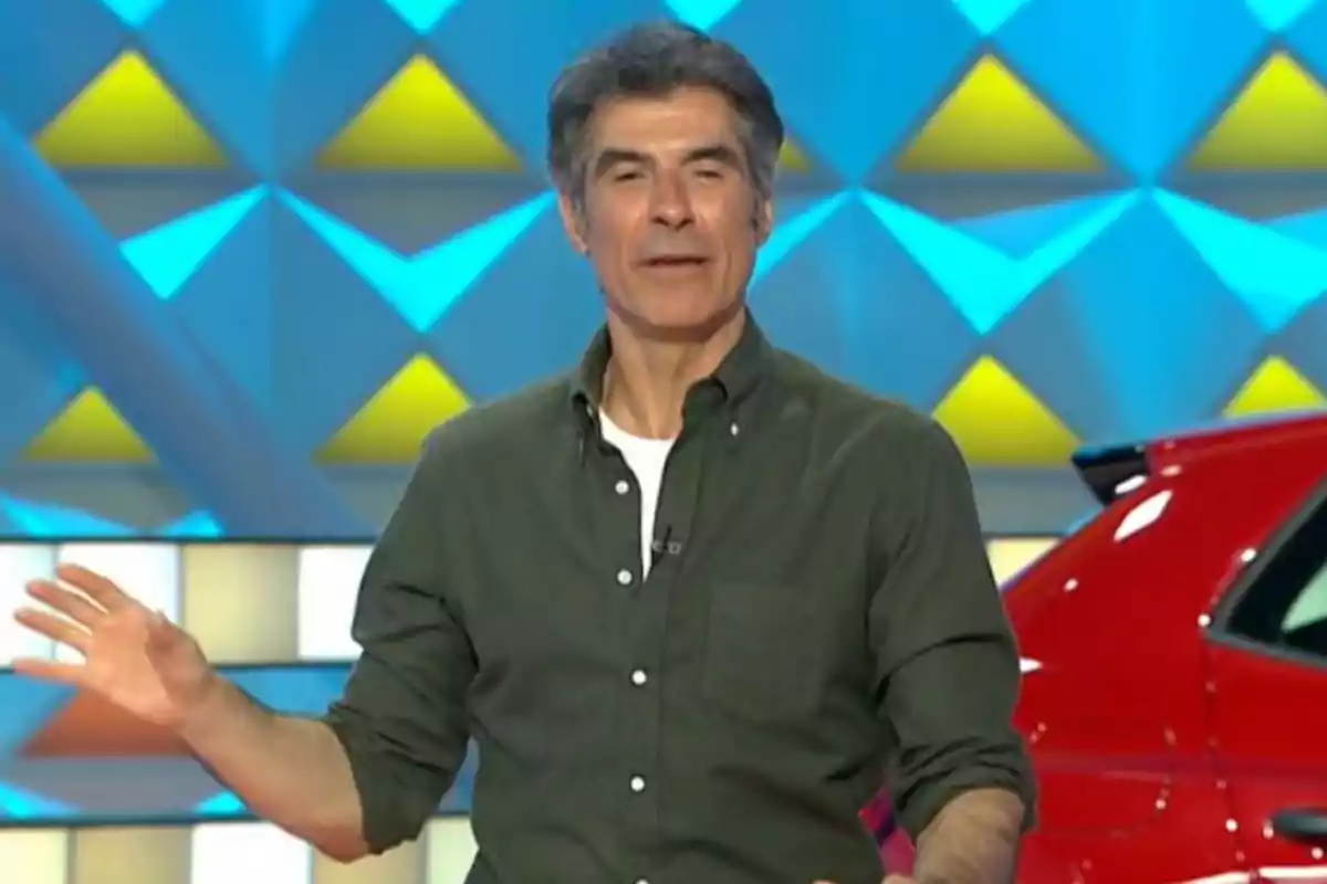 Jorge Fernández con camisa verde oscuro y camiseta blanca de fondo en un set colorido junto a un auto rojo. Captura de 'La Ruleta de la Suerte' Jorge Fernández con camisa verde oscuro y camiseta blanca de fondo en un set colorido junto a un auto rojo. Captura de 'La Ruleta de la Suerte'