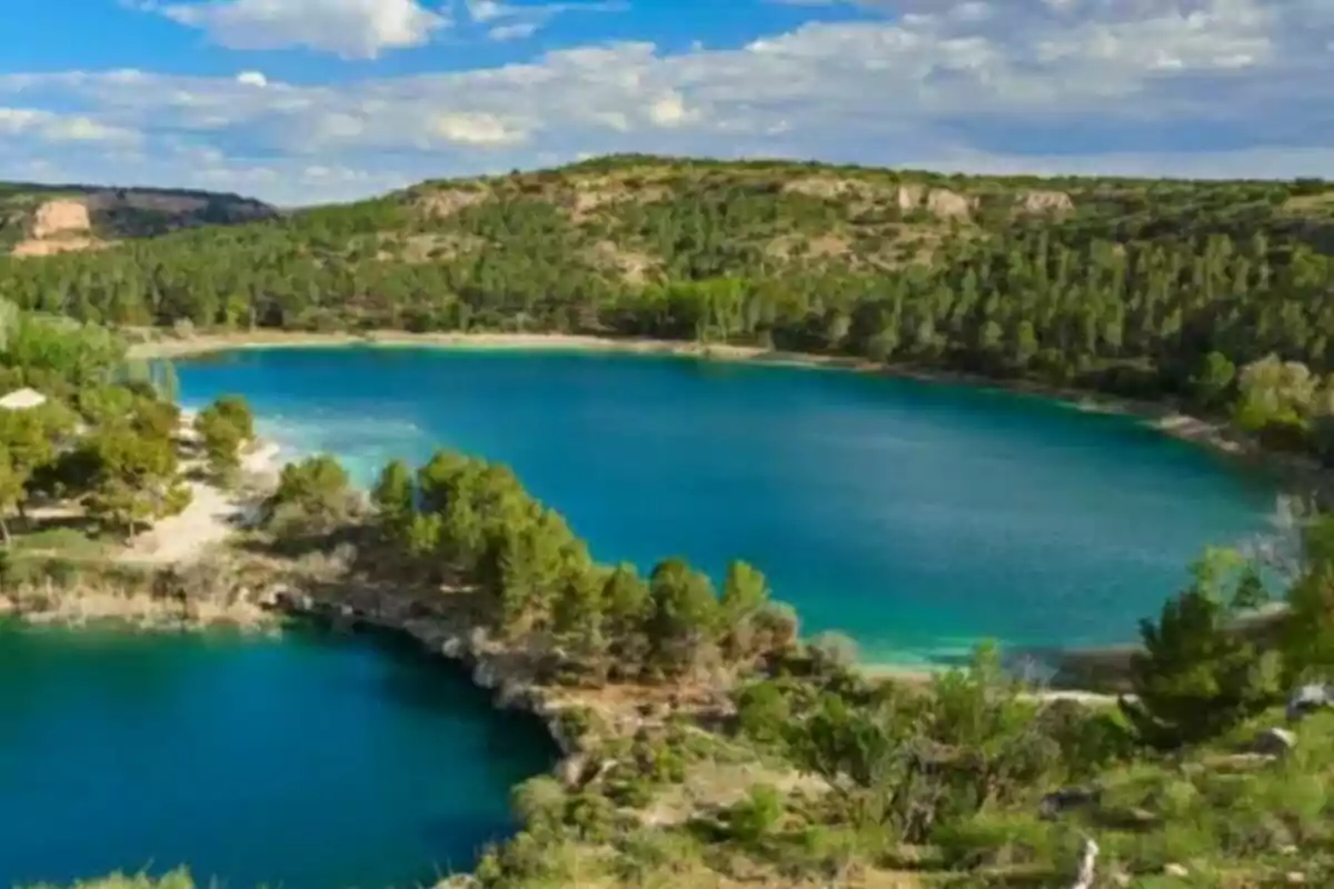 Lago rodeado de colinas y vegetación con cielo parcialmente nublado.