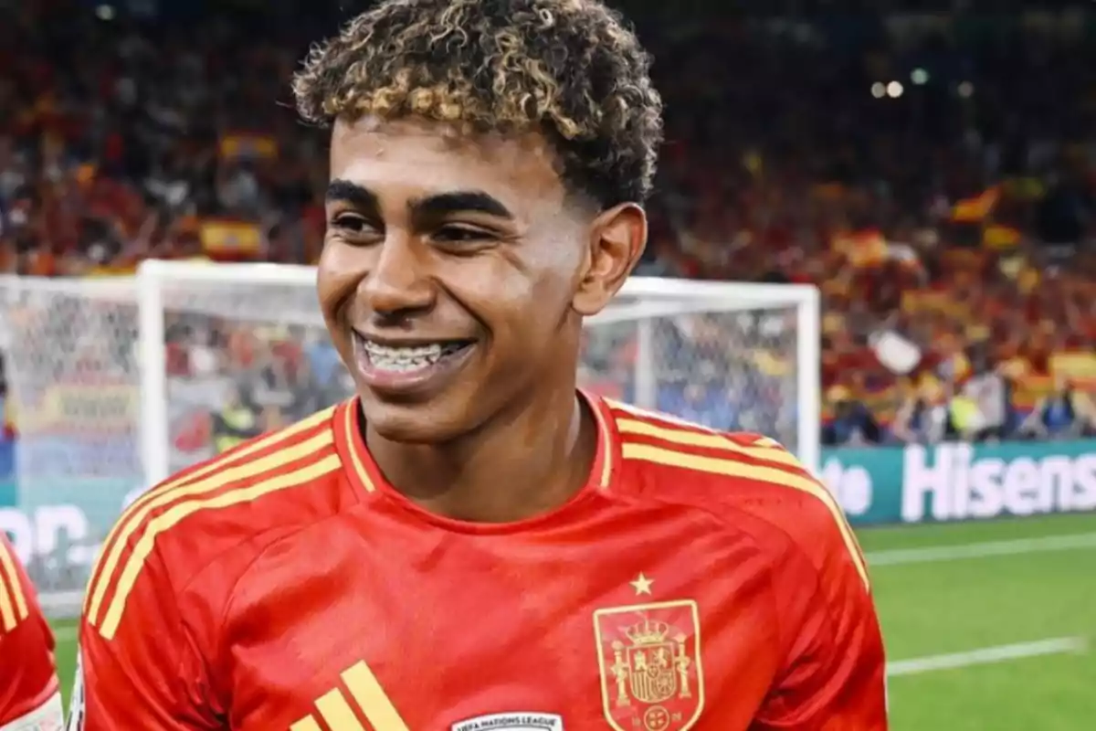 Un jugador de fútbol sonríe mientras viste el uniforme de la selección de España en un estadio.